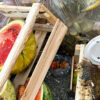 Discarded fruits, vegetables, and wooden produce crates in a food waste collection area for organics recycling.