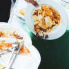 Leftover food scraped from dinner plates into a collection bin for food waste recycling or composting.