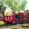 Tracked wood grinder processing material with excavator