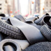 Pile of recycled rubber tires, rubber strips and crumb rubber material illustrating tire recycling and devulcanization processes.