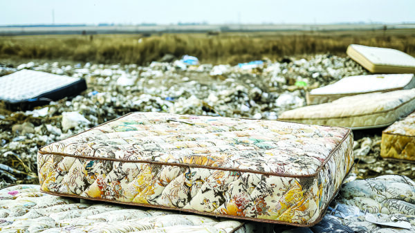 Discarded mattresses awaiting recycling at a mattress waste recovery facility