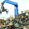 Hydraulic crane handling scrap metal at a recycling yard amid growing demand for recycled materials