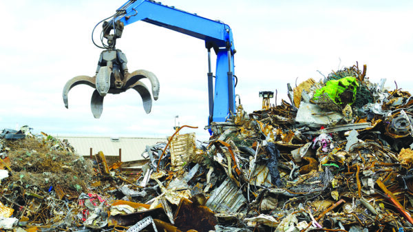 Hydraulic crane handling scrap metal at a recycling yard amid growing demand for recycled materials