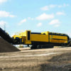 Tracked industrial screening machine processing material into stockpiles at an outdoor recycling operation