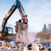 Excavator sorting construction and demolition debris for recycling at a material recovery facility.