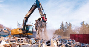 Excavator sorting construction and demolition debris for recycling at a material recovery facility.