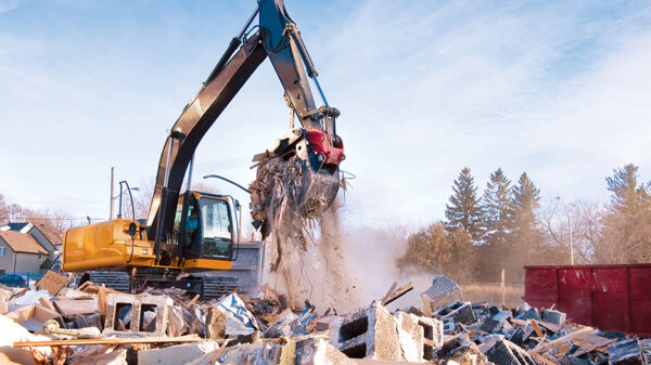 Excavator sorting construction and demolition debris for recycling at a material recovery facility.