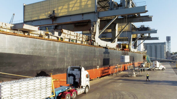 Steel coils being loaded onto a cargo ship at a port for international steel imports.
