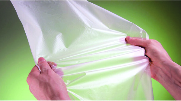 Hands stretching a sheet of plastic film representing post consumer plastic recycling.