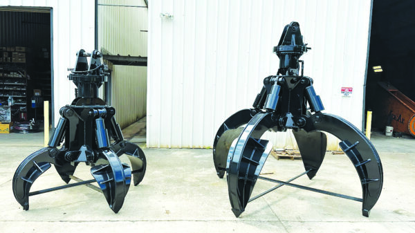 Two heavy-duty orange-peel grapples used for handling scrap metal and other bulk recycling materials