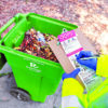 Worker inspecting a Recology compost cart as part of the company's sustainability and recycling operations.