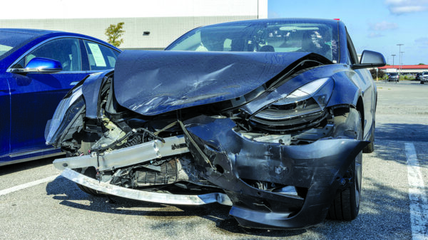Wrecked high-tech electric vehicle awaiting dismantling at an auto recycling facility.