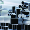 Stacked aluminum extrusions and metal profiles representing the U.S. aluminum supply chain and recycling industry.