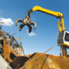 Material handler with grapple loading scrap metal at a recycling yard.