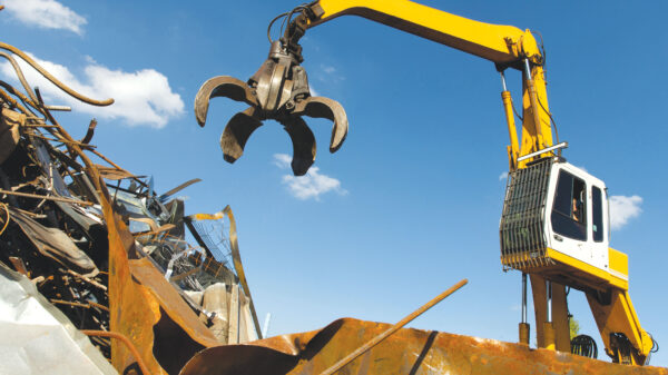Material handler with grapple loading scrap metal at a recycling yard.