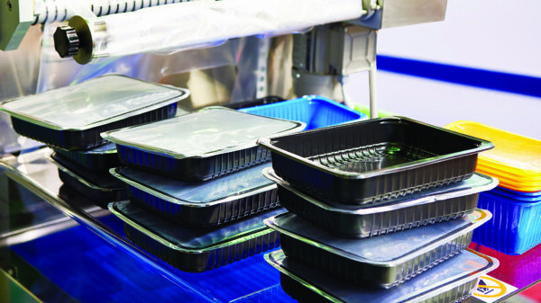 Plastic food packaging trays on industrial processing equipment for packaging production